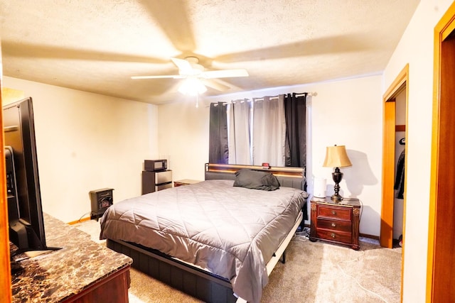 carpeted bedroom featuring a textured ceiling and ceiling fan