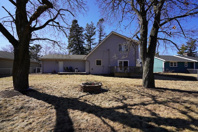 back of property featuring an outdoor fire pit, fence, and a deck