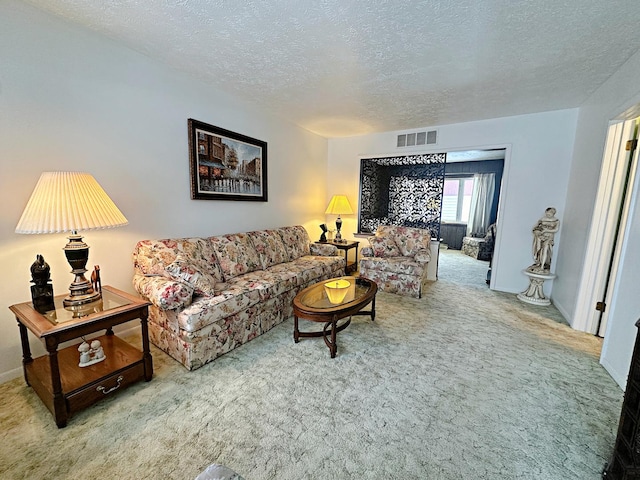 living area with baseboards, visible vents, a textured ceiling, and light colored carpet