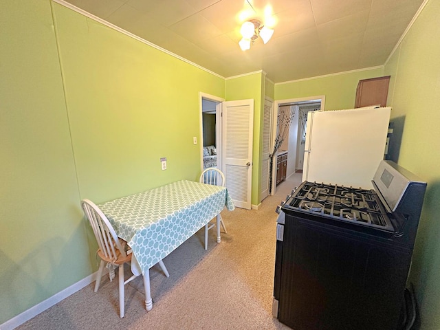 kitchen with light carpet, baseboards, ornamental molding, freestanding refrigerator, and stainless steel gas range