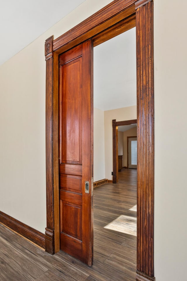 hallway with dark wood-style flooring and baseboards