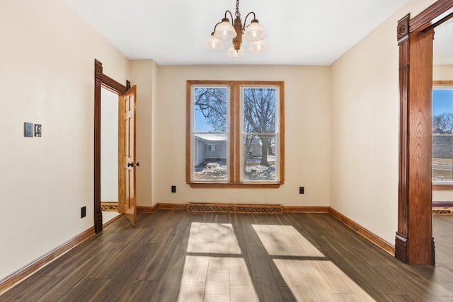 unfurnished dining area with an inviting chandelier, baseboards, dark wood finished floors, and a baseboard heating unit