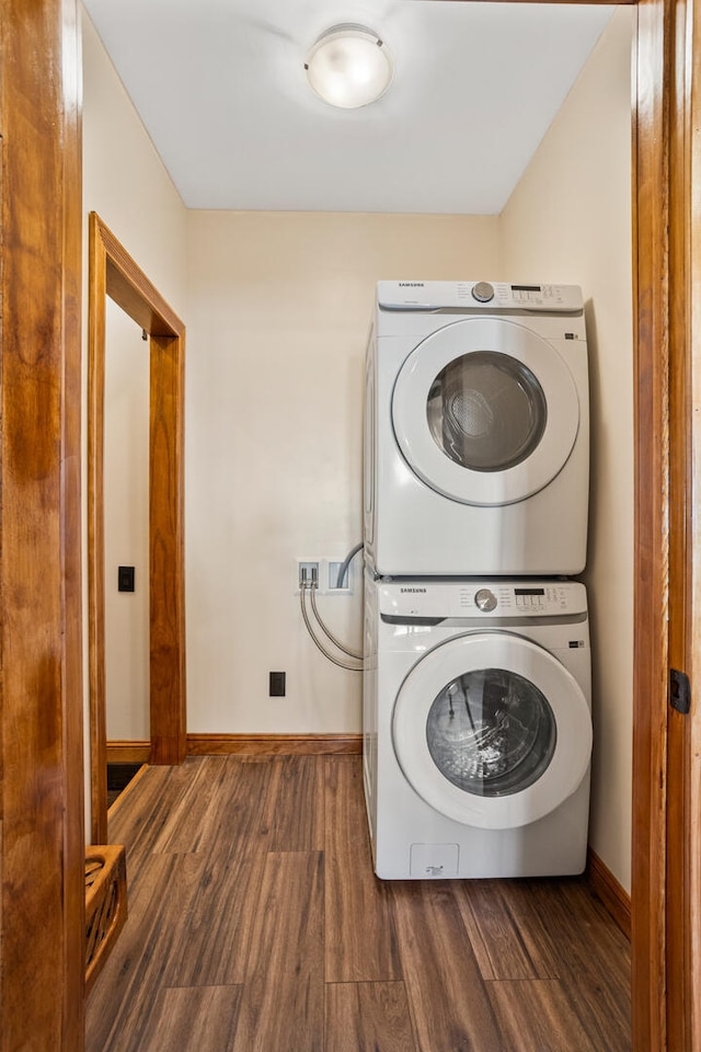 laundry room with stacked washer and dryer, baseboards, and dark wood-style floors