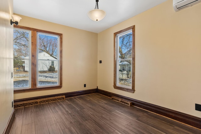 unfurnished room with visible vents, baseboards, dark wood finished floors, and a wall mounted AC