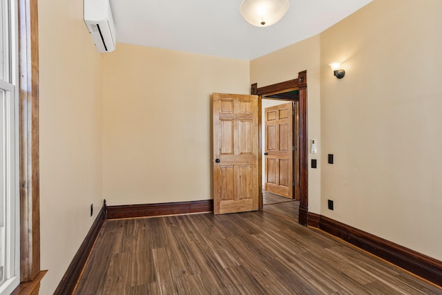 unfurnished room featuring dark wood finished floors, baseboards, and a wall mounted AC