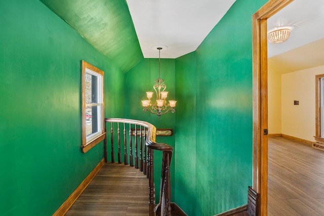 staircase with lofted ceiling, baseboards, an inviting chandelier, and wood finished floors