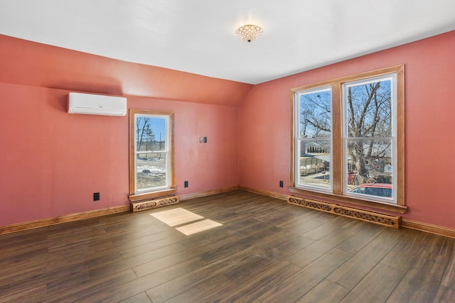 spare room with dark wood-style floors, an AC wall unit, vaulted ceiling, and baseboards