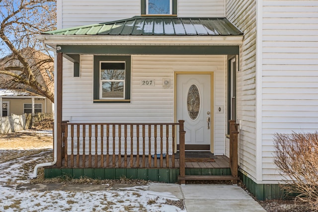 snow covered property entrance with a porch and metal roof