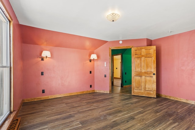 empty room with lofted ceiling, visible vents, dark wood finished floors, and baseboards