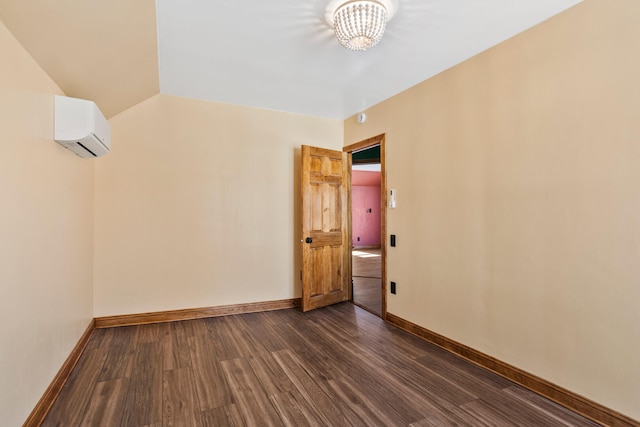 empty room with lofted ceiling, a wall mounted air conditioner, dark wood finished floors, and baseboards