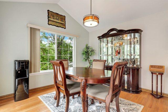 dining room with light hardwood / wood-style flooring and vaulted ceiling