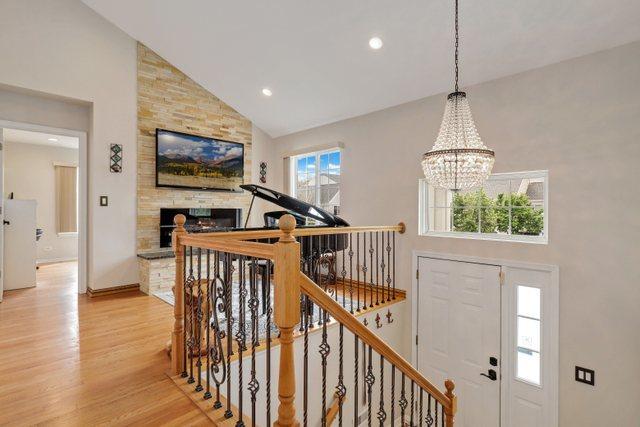 interior space with a stone fireplace, high vaulted ceiling, a chandelier, and light wood-type flooring