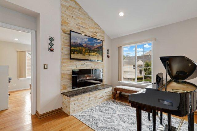 living area featuring a fireplace, vaulted ceiling, and light wood-type flooring