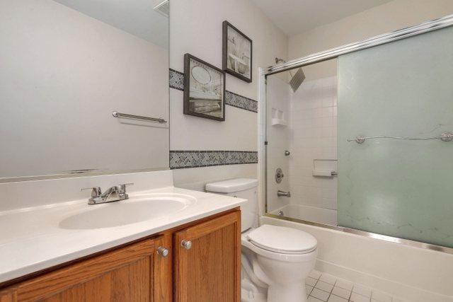 full bathroom featuring vanity, tile patterned floors, shower / bath combination with glass door, and toilet