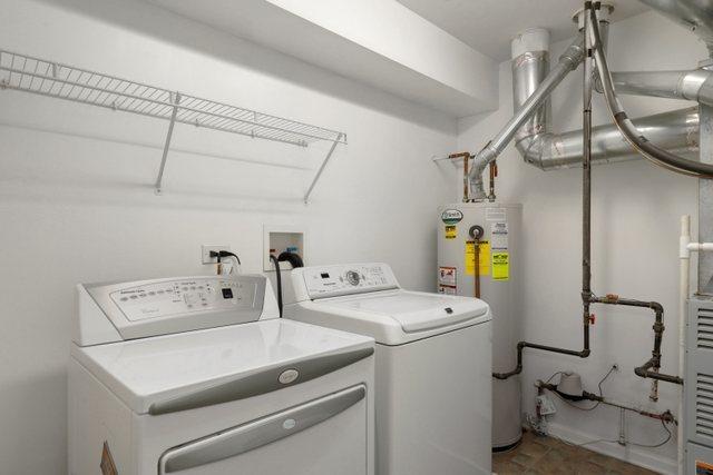 clothes washing area with washer and dryer and gas water heater