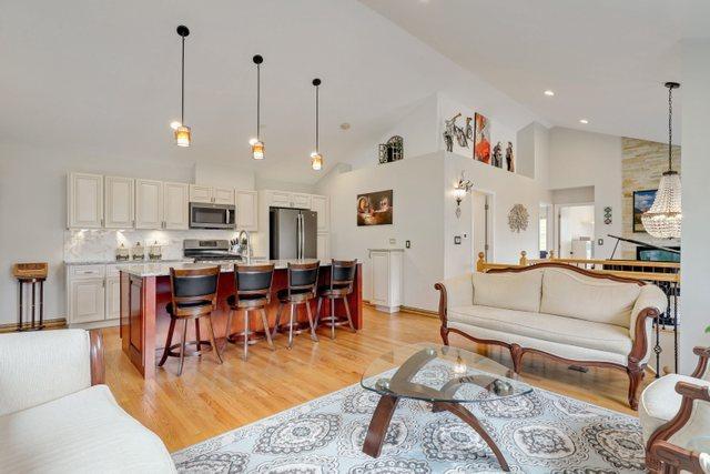 living room with high vaulted ceiling, sink, and light hardwood / wood-style floors