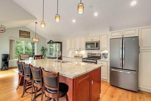 kitchen featuring stainless steel appliances, sink, pendant lighting, and a kitchen island with sink