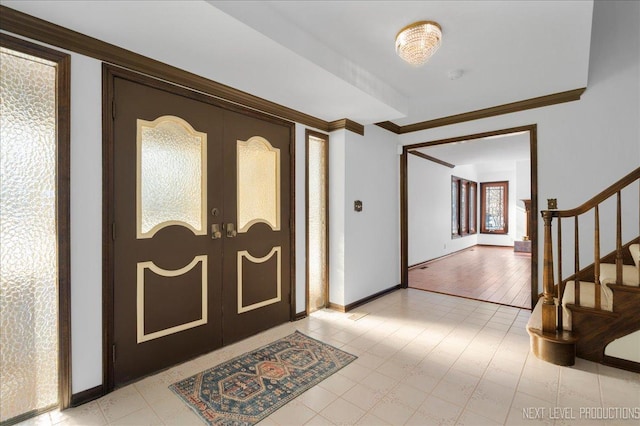 entrance foyer with ornamental molding, french doors, stairway, and baseboards