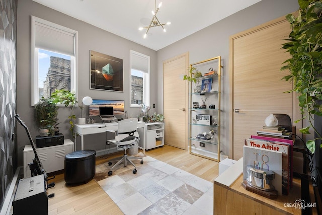 office area with a wealth of natural light, a notable chandelier, and light wood-type flooring