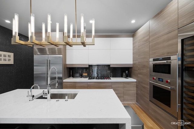 kitchen featuring pendant lighting, sink, an island with sink, and appliances with stainless steel finishes