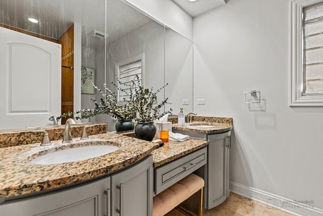 bathroom featuring tile patterned floors, two vanities, a sink, and baseboards