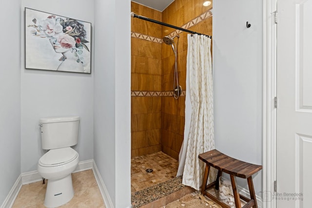 bathroom featuring toilet, baseboards, a tile shower, and tile patterned floors