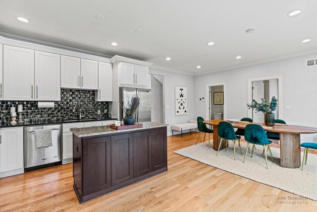 kitchen featuring appliances with stainless steel finishes, light wood-type flooring, a sink, and ornamental molding