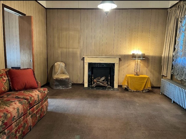 carpeted living room with radiator heating unit, a premium fireplace, and wooden walls