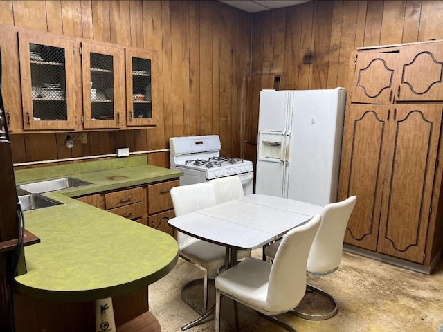 kitchen featuring white appliances, sink, and wood walls