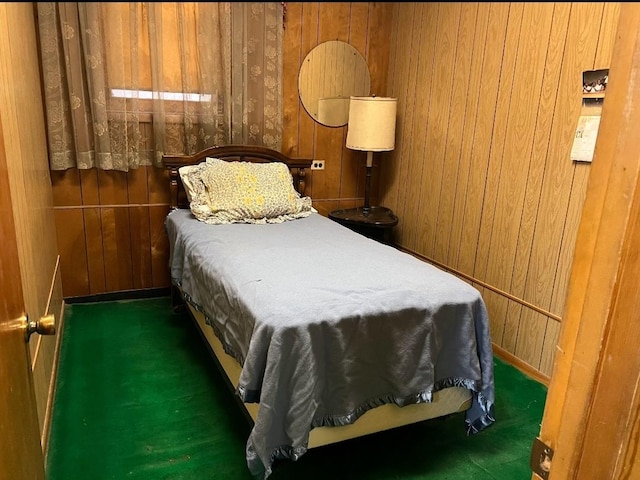 bedroom with dark colored carpet and wooden walls