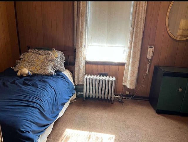 bedroom with carpet flooring, radiator heating unit, and wooden walls