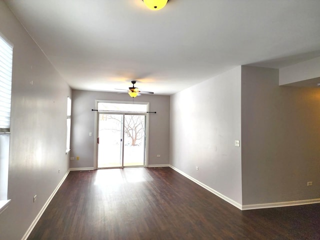 unfurnished room featuring baseboards and dark wood-style flooring