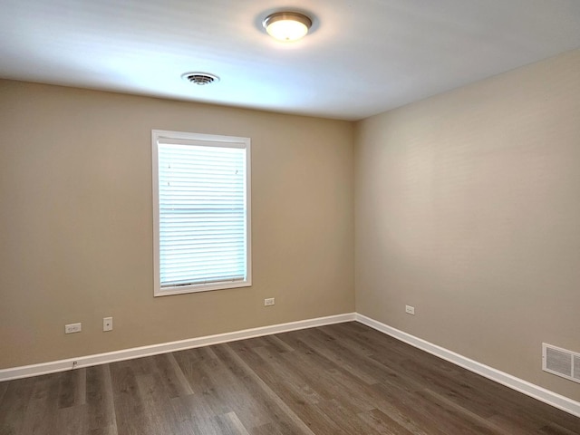 empty room with baseboards, visible vents, and dark wood-style flooring