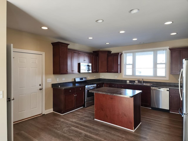 kitchen with dark countertops, a kitchen island, appliances with stainless steel finishes, and dark wood-style flooring