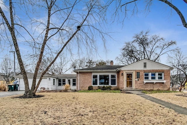 view of front of home featuring driveway, brick siding, a chimney, and an attached garage