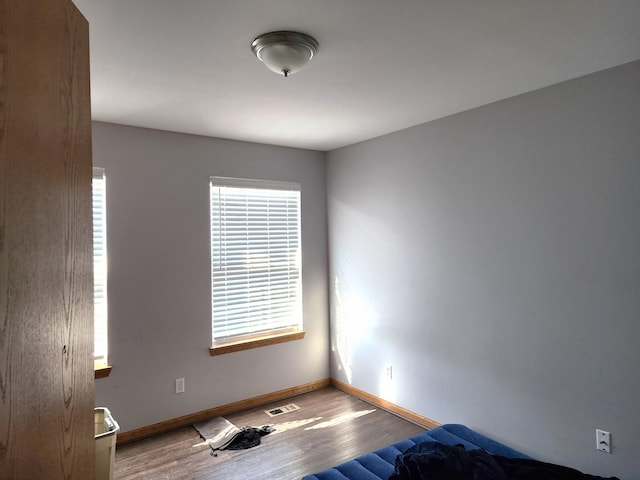 unfurnished room with wood finished floors, visible vents, and baseboards