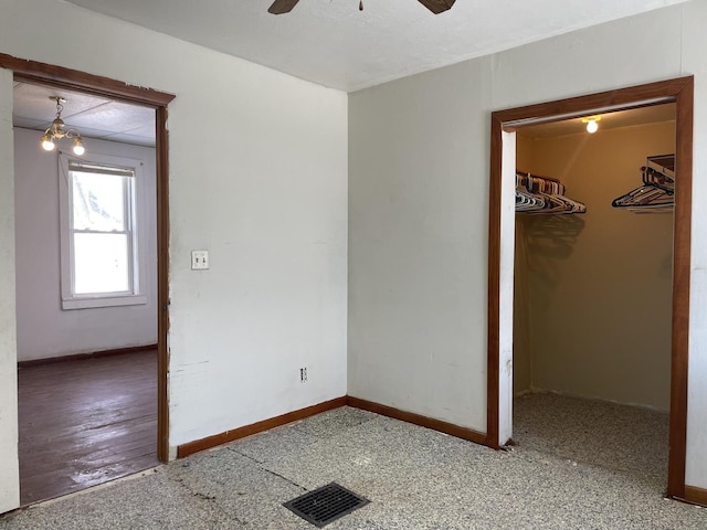 unfurnished bedroom with a walk in closet, a closet, and ceiling fan