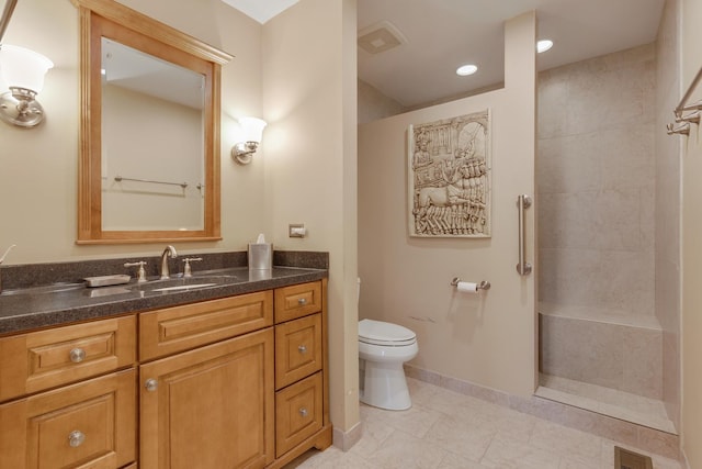 bathroom featuring tiled shower, vanity, and toilet