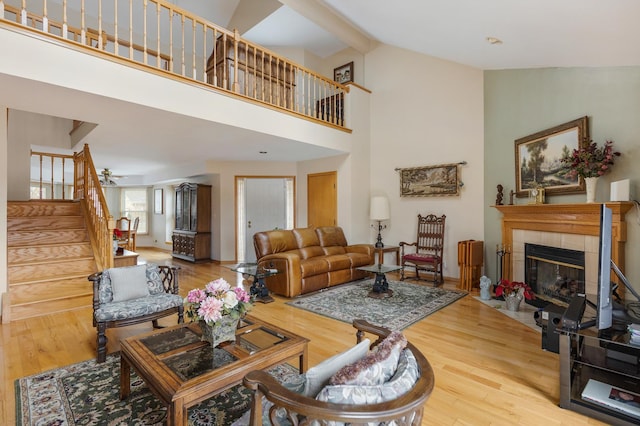 living room with hardwood / wood-style flooring, a tiled fireplace, and high vaulted ceiling