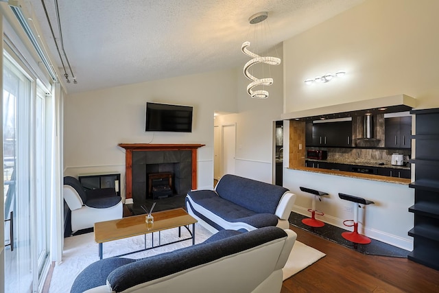 living room with a tile fireplace, high vaulted ceiling, a textured ceiling, dark hardwood / wood-style flooring, and a chandelier