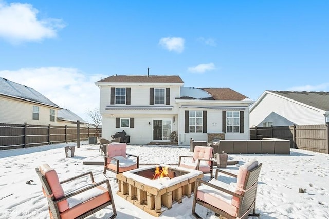 snow covered rear of property with an outdoor fire pit