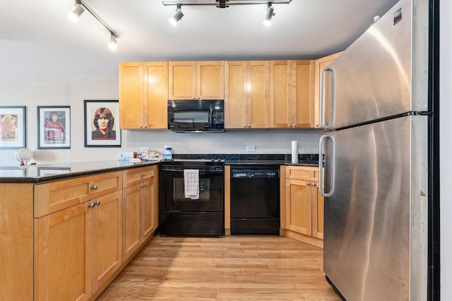 kitchen with dark stone countertops, light brown cabinetry, light hardwood / wood-style floors, and black appliances