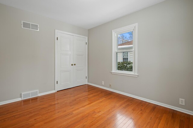 unfurnished room featuring light wood-style flooring, visible vents, and baseboards