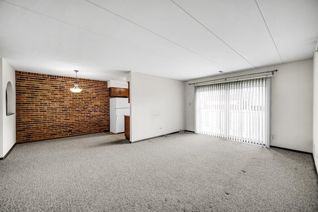 unfurnished living room with brick wall, baseboards, and light colored carpet