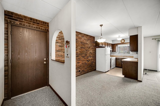 kitchen featuring light carpet, brick wall, light countertops, and freestanding refrigerator