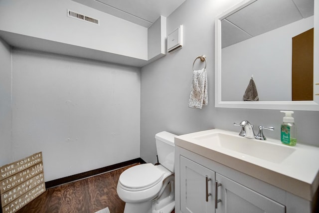 bathroom with visible vents, toilet, vanity, wood finished floors, and baseboards