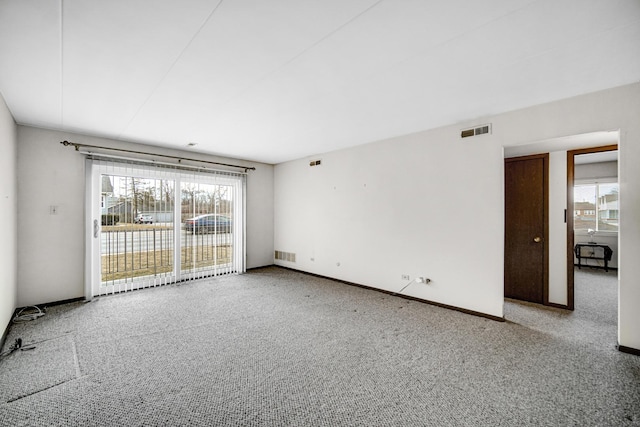 carpeted spare room featuring baseboards and visible vents