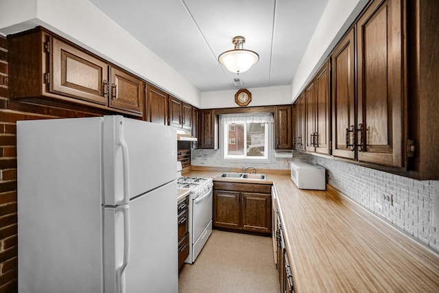 kitchen with light countertops, a sink, dark brown cabinetry, white appliances, and under cabinet range hood