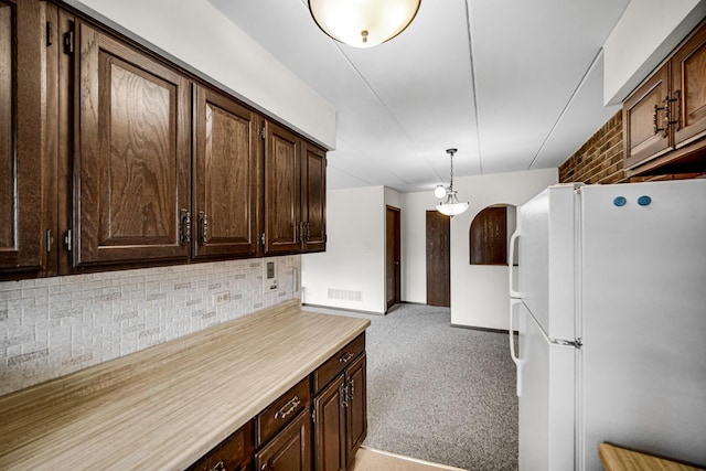 kitchen with dark brown cabinetry, visible vents, decorative backsplash, light colored carpet, and freestanding refrigerator