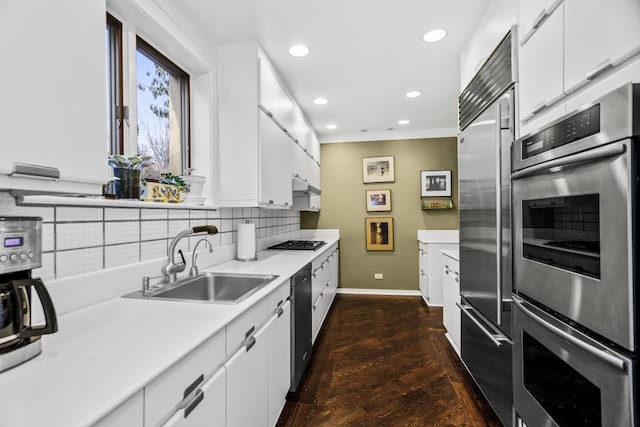 kitchen with a sink, white cabinets, light countertops, appliances with stainless steel finishes, and decorative backsplash